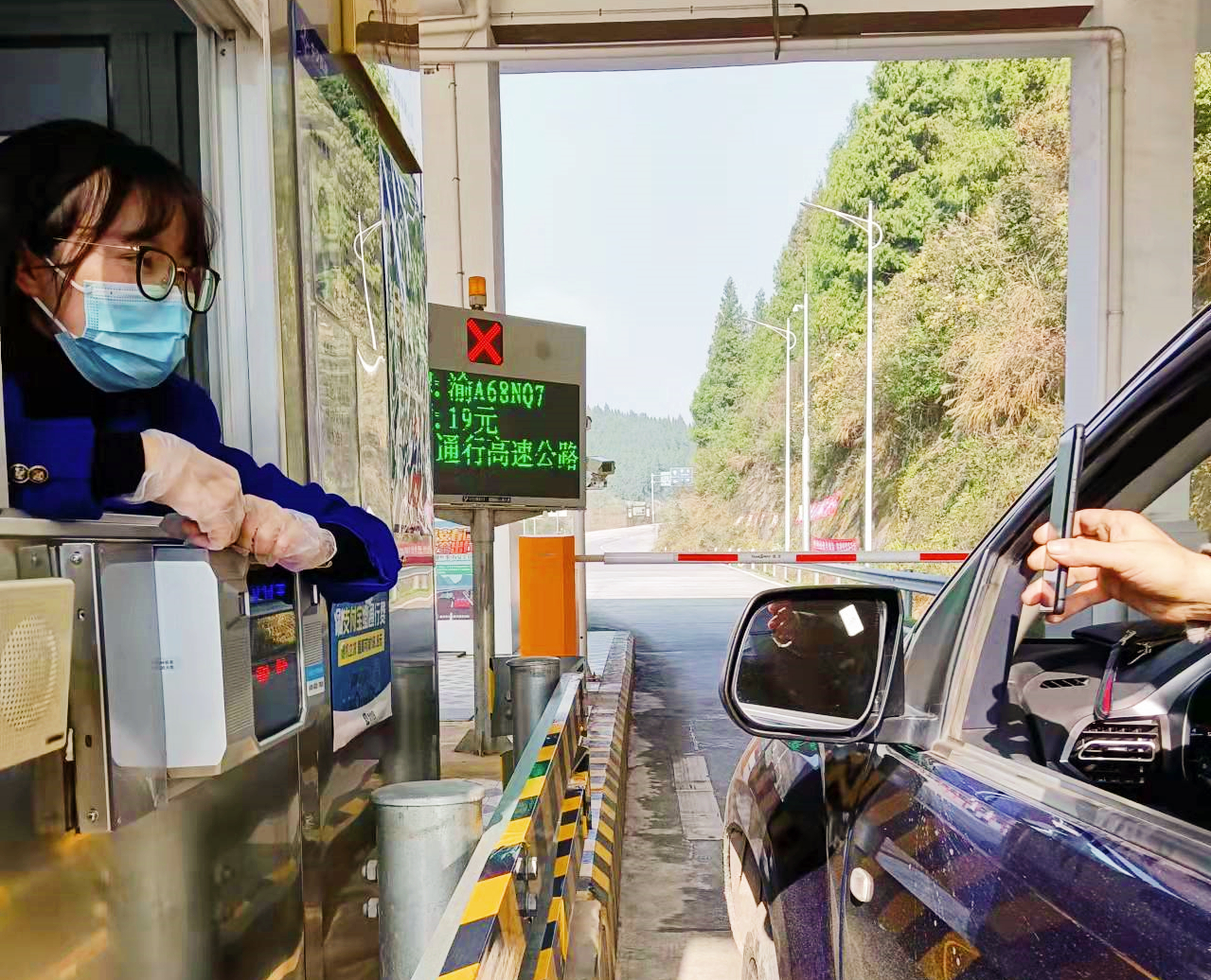 春运首日,忠万高速新乡站收费员检查返乡人员渝康码.